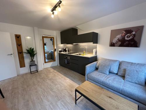 a living room with a blue couch and a kitchen at MEINpartments - Full service living in Wolfsburg