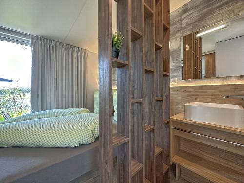 baño con lavabo, cama y espejo en Tiny house with lake view in holiday village in Bavaria, en Neunburg vorm Wald