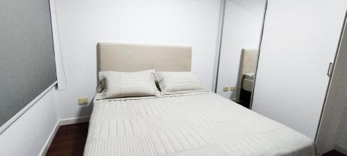 a small white bed in a room with a mirror at Hermoso departamento en Skytower in Asunción