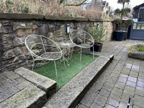 two chairs and a table in front of a stone wall at Lilimae Barn in Ashbourne