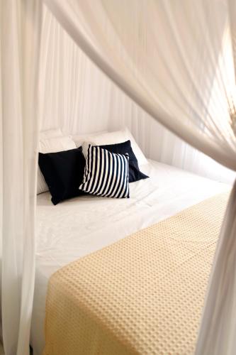 a bed with black and white pillows on it at Villa Joá - Casa no Quadrado in Trancoso