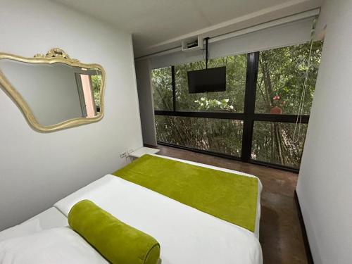 1 dormitorio con cama, espejo y ventana en Room in BB - Suite Presidencial en hotel proximo al aeropuerto, en San Antonio de Pereira