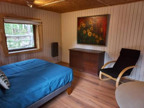 1 dormitorio con 1 cama, 1 silla y 1 pintura en Conguillio cabaña Concón Turismo Conguillio, en Santa María