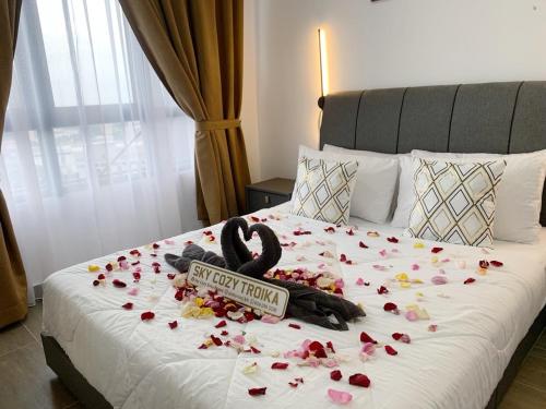 uma cama com flores com um cartaz em SKY COZY TROIKA RESIDENCE, 1 BEDROOM 4-6 PAX, 2 BEDROOMS 6-8 PAX, POOL VIEW, SKY & CITY VIEW, Free Parking, Pool, WiFi, Netflix, Disney Hotstar em Kota Bharu