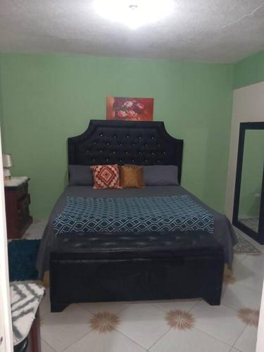 a bedroom with a black bed in a room at Willow tree quiet and peaceful in Montego Bay