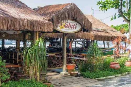 a restaurant with a straw building with plants in front at Pitangueiras Guarujá próximo da praia in Sao Paulo