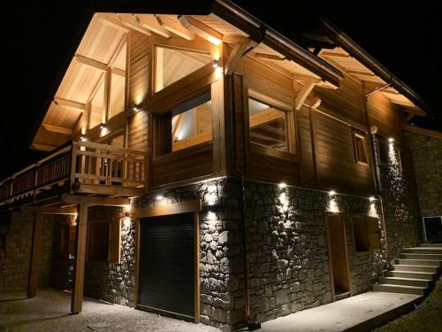 a wooden house with a staircase in front of it at night at Superbe chalet avec vue montagne in Orcières