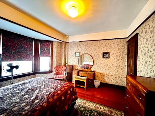 a bedroom with a bed and a desk and a mirror at Arundel Mansions Hotel in New Westminster