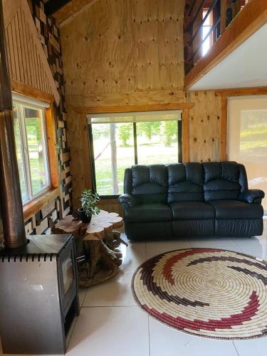 sala de estar con sofá negro y TV en Cabaña El Polux, ruta x-671, en Coyhaique