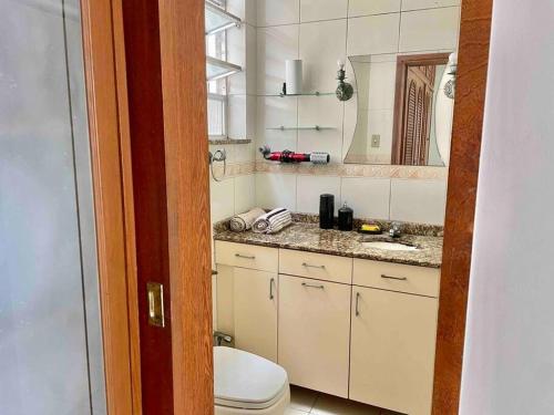een badkamer met een toilet, een wastafel en een spiegel bij Apartamento Inteiro na Praia de Icaraí com Vista in Niterói