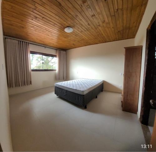a bedroom with a bed in a room with a wooden ceiling at Casa Alto do Campo - Lavras Novas MG in Lavras Novas