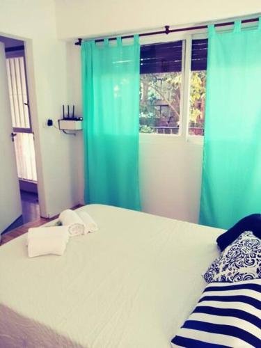 1 dormitorio con 1 cama con cortinas azules y ventana en La Casa de Malena en Buenos Aires