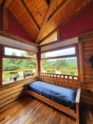 ein Bett in einem Holzzimmer mit zwei Fenstern in der Unterkunft Talasuas -aires de montaña in Villa General Belgrano