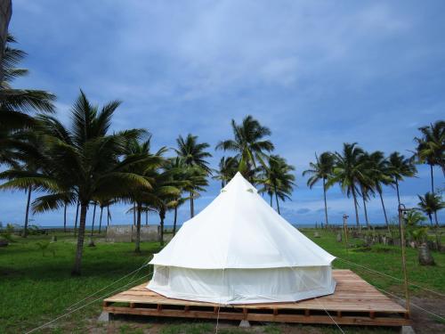 a white tent on a wooden platform with palm trees at Glamping La Isla Bonita (Isla Portete, Ecuador) in Zapotal