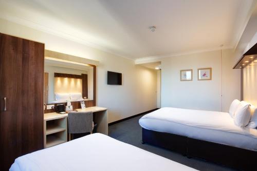 a hotel room with two beds and a desk at Royal National Hotel in London