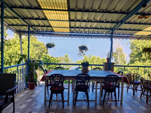 a table and chairs on a screened porch with a view at The Shire Kalimpong in Kalimpong