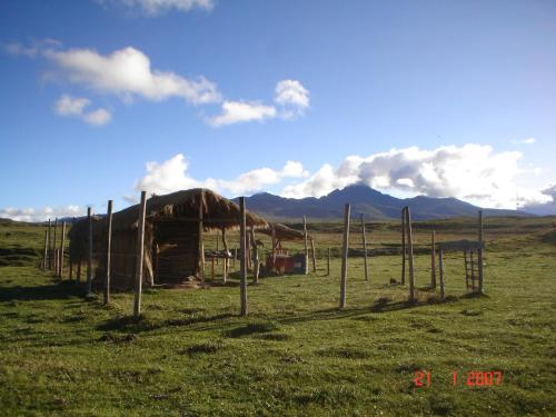 a wooden hut in a field with mountains in the background at Hacienda Yanahurco in Ovejería