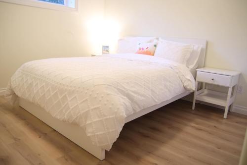 a bed with a white comforter and a side table at A private suite in Port Moody in Port Moody