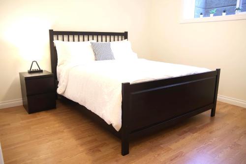 a bed with a black frame and a white comforter at A private suite in Port Moody in Port Moody
