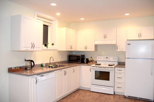 a kitchen with white cabinets and white appliances at A private 2-bedroom suite in Port Moody in Port Moody