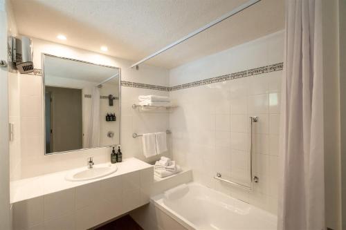a white bathroom with a sink and a mirror at Edgewater Hotel in Wanaka