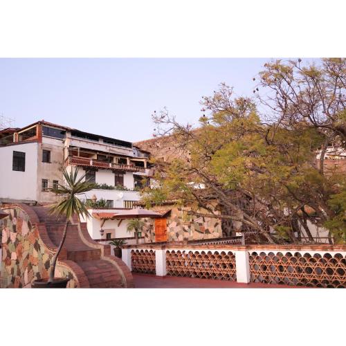 a view of a building with a fence and trees at Hotel los Arcos in Taxco de Alarcón