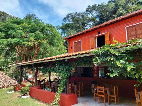 budynek ze stołami i krzesłami przed nim w obiekcie Pousada, Camping e Restaurante do Sô Ito w mieście Santa Rita de Jacutinga