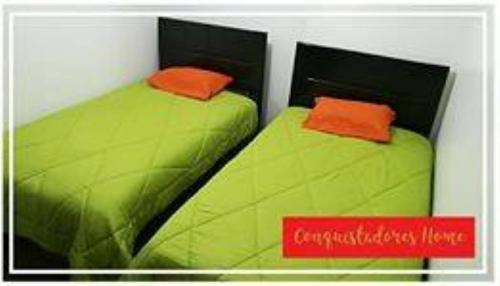 duas camas verdes com almofadas laranja sentadas ao lado uma da outra em conquistadores home em Cusco