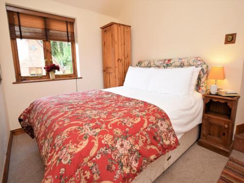 een slaapkamer met een bed met een rode deken en een raam bij 1 bed property in Banbury CC072 in Shotteswell