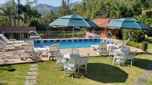 a group of chairs and tables with umbrellas next to a pool at Pousada Beija Flor - Lumiar in Lumiar