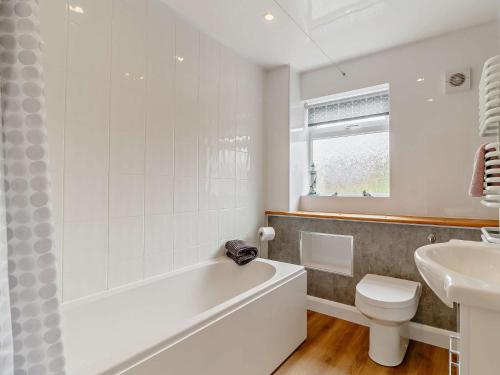 een badkamer met een bad, een toilet en een wastafel bij 2 Bed in Cromer DAIN8 in Northrepps