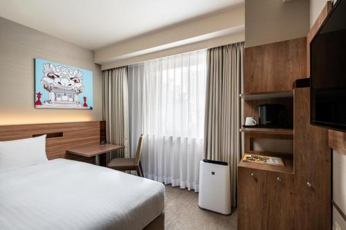 a hotel room with a bed and a television at Noku Osaka in Osaka