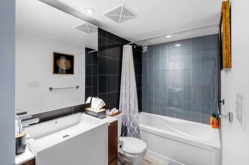 een badkamer met een bad, een toilet en een wastafel bij One Bed and Den Upscale Comfort Condo with Parking in Toronto