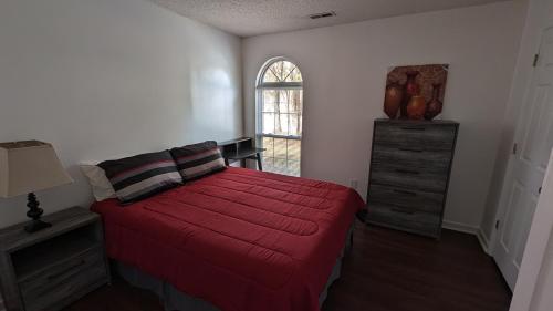 1 dormitorio con cama roja y ventana en Haven - Uptown/Airport Corridor en Charlotte