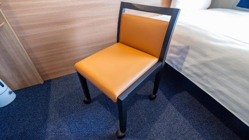 an orange chair in a room next to a bed at Toyoko Inn Osaka Yodoyabashi-eki Minami in Osaka