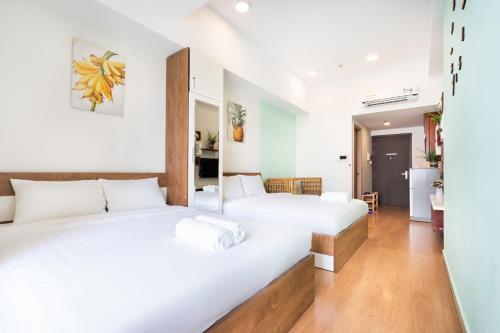 two beds in a room with white walls and wooden floors at Genius Apartment River Gate Free Pool in Ho Chi Minh City