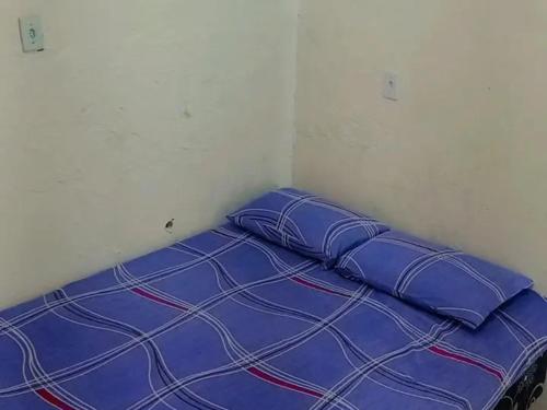 a bed with blue pillows in a room at Kitnet no Centro de São Pedro da Aldeia De frente para Lagoa in São Pedro da Aldeia