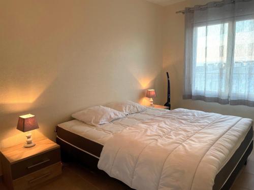 une chambre avec un lit blanc avec deux tables de nuit dans l'établissement Bel appartement 1 chambre tout confort au bord de la mer avec balcon et parking - FR-1-323-216, à Saint-Jean-de-Monts