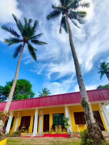 a building with two palm trees in front of it at Jurisu Resort in San Vicente