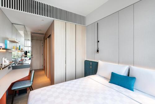 a bedroom with a white bed and a kitchen at TOWNPLACE WEST KOWLOON in Hong Kong