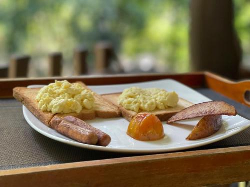 a plate of food with sausage eggs and bread at The Mastodon Valley Safari Resort in Udawalawe