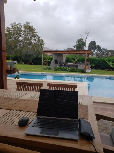 un ordenador portátil sentado en una mesa junto a una piscina en Casa de campo Oasis De San Andres, en Miraflores