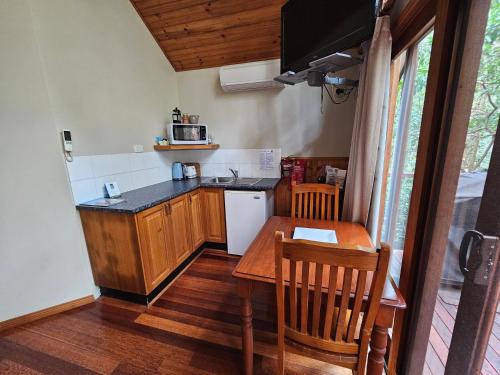 a small kitchen with a table and a microwave at Wanderers Retreat in Nelson Bay