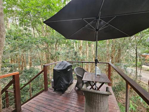a wooden deck with a table and an umbrella at Wanderers Retreat in Nelson Bay