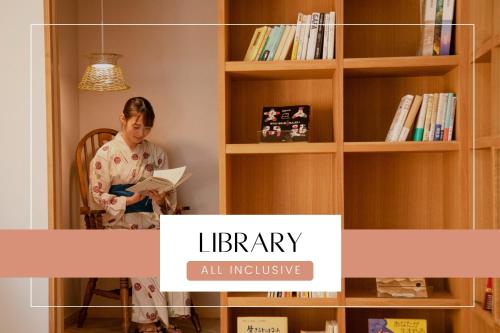 a woman sitting in a chair reading a book in a library at Ichiraku tendo spa & brewery in Tendo