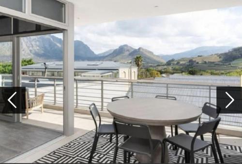 d'un balcon avec une table, des chaises et des montagnes. dans l'établissement Franschhoek - La Petit Village - Views, à Franschhoek