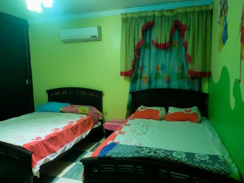 2 Betten in einem Zimmer mit grünen Wänden in der Unterkunft شقه غرفتين نوم in Kairo