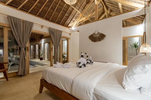 a bedroom with a large bed with two stuffed animals on it at Villa Kelapa Kucing in Gili Air
