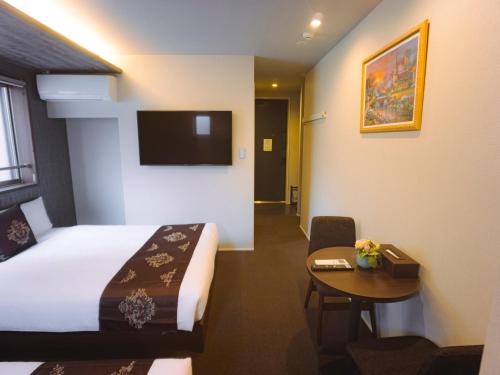 um quarto de hotel com uma cama e uma mesa e uma televisão em GRAND BASE Hakata Bay em Fukuoka