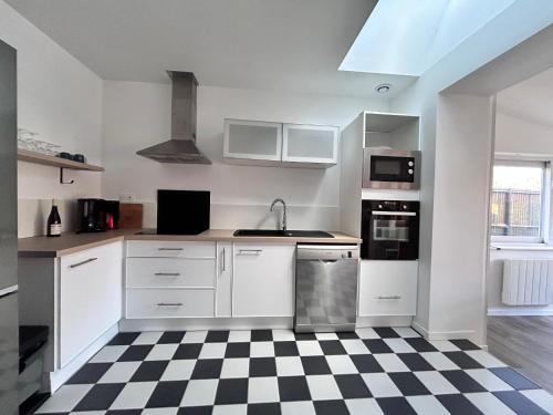 - une cuisine avec des placards blancs et un sol en damier dans l'établissement Maison rénovée 4 ch. avec jardin, à 700m de la plage et proches commerces - St Brevin Les Pins - FR-1-364-152, à Saint-Brévin-les-Pins